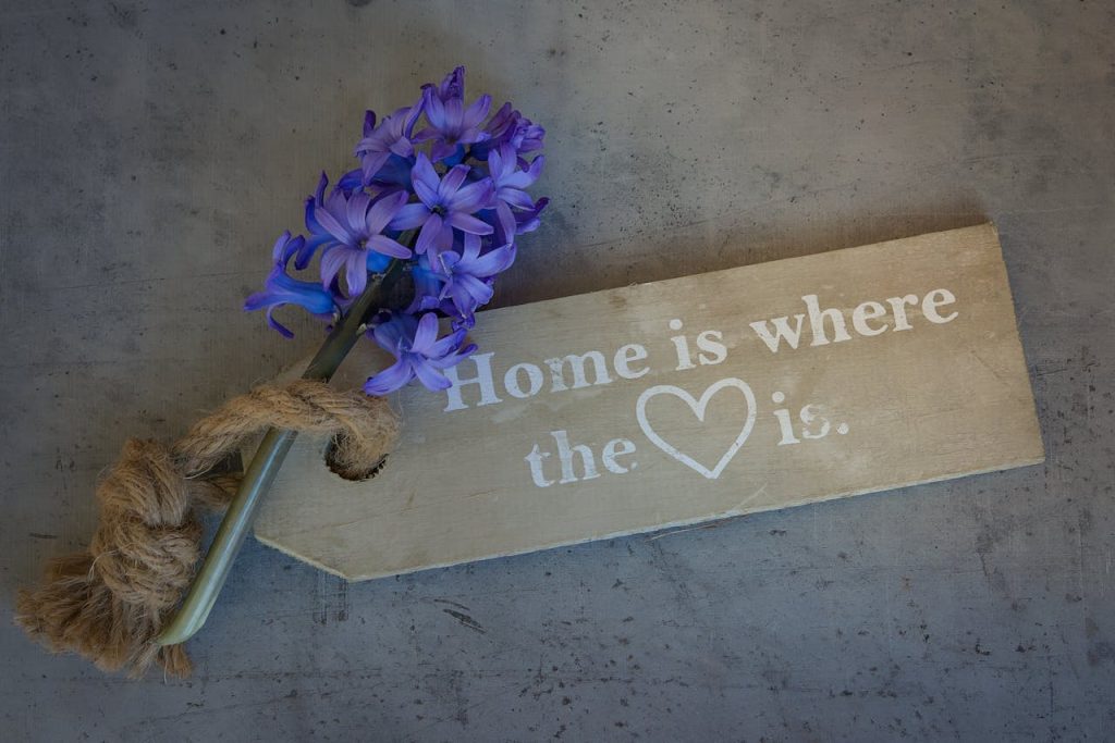 A rustic sign with purple hyacinths and twine, symbolizing home comfort and happiness.
